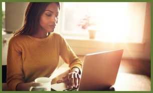 Female utilizing a laptop computer while drinking her morning coffee